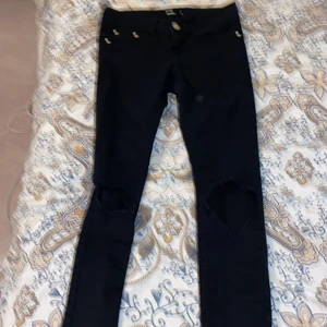 Svarta jeans storlek s - Svarta jeans med hål på knäna, lågmidjade