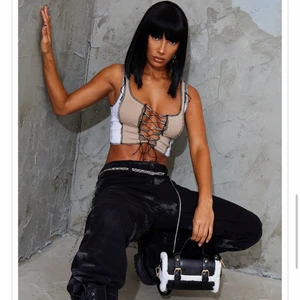 Crop top med snörning fram - Säljer en crop top från PrettyLittleThing. Beige/vit men svart snörning framtill. Väldigt stretchig & bekväm men inte riktigt min stil. Aldrig använd! Köptes för £9 ≈ 111kr därav säljer jag för 110kr inklusive frakt då det inte finns några defekter💕