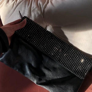 Väska - Jättefin svart Axelväska, går att ha med kort eller lång rem. Fint skick, är vintage med några diamantdekorationer på framsidan!💕 Kontakta privat vid intresse. 