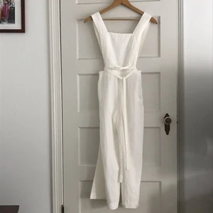 Vit linne jumpsuit från bershka - En superfin jumpsuit från bershka som tyvärr aldrig kommit till användning, alltså ALDRIG ANVÄND! Axelbanden kan bäras i kors eller raka i ryggen! Band runt midjan och längd på axelbanden kan justeras då det finns två stycken knapphål för axelbanden! Storlek xs! PERFEKT TILL STUDENTEN😍