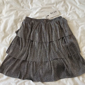 Volangkjol - Silvrig volangkjol från NA-KD i nyskick, lapp kvar och aldrig använd. Säljs ej längre. Har du några frågor är det bara att skriva, priset är exkl frakt😊