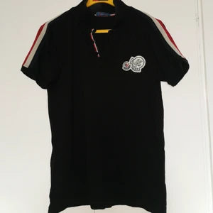 Moncler pike  - Hej grabbar! Eller tjejer som vill köpa något fint till sin bror, pappa eller pojkvän, svart moncler pike t-shirt med röda & vita detaljer. använd endast några gånger bara och den passar tyvärr inte min kille längre