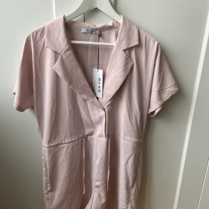 Byxdress från NAKD - Oanvänd byxdress från NA-KD. Går att knyta i midjan. Har fickor. Storlek 36