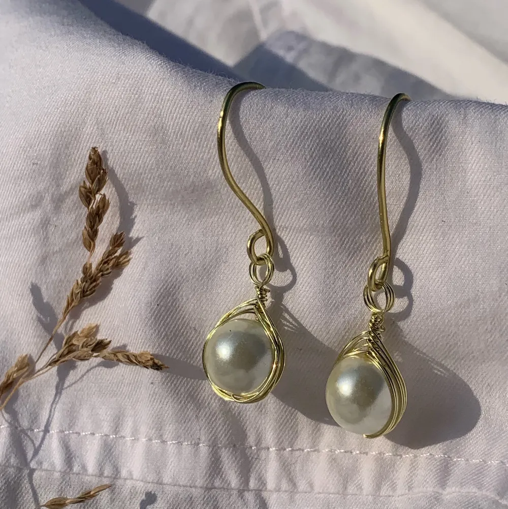Handgjorda örhängen med offwhite pärlor, och guldpläterad koppartråd. Nickel-, kadium-, och blyfria. 2x1,5cm. Accessoarer.