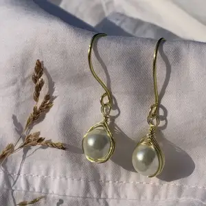 Handgjorda örhängen med offwhite pärlor, och guldpläterad koppartråd. Nickel-, kadium-, och blyfria. 2x1,5cm