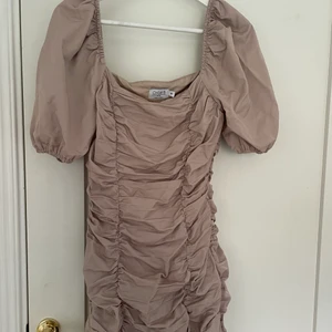 Beige klänning nakd - Klänningen är endast använd 2 gånger på en tjejerna i Kroatien. Klänningen har en fyrkantig urringning och sitter tajt men ballong ärm.