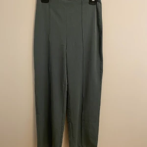 Gröna kostymbyxor  - Ett par gröna högmidjade långa kostymbyxor som lätt kan få en tråkig outfit att se roligare ut.