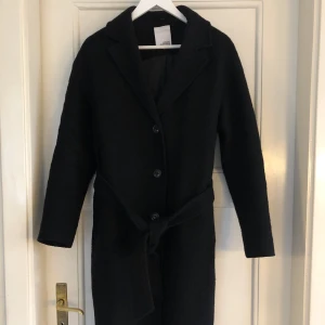 Svart ullkappa - Svart ullkappa från Visual Clothing Project med bälte som går att knäppa utan bälte också. Når till knäna på mig som är 173, sparsamt använd så i jättebra skick💜lite oversize så passar S/M, nypris 1500. Skriv vid frågor eller för fler bilder🤗