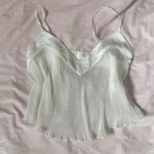 Vitt linne - Ett vitt linne från zara med väckat tyg och små prickar. Volang-modell och v-ringat.  Reglerbara axelband och lite halvt genomskinligt tyg. 💓 