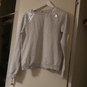 Grå glittrig tjocktröja - En grå tjocktröja med paljeter på axlarna jätte fin och skön oandvänd (står inte för frakten)