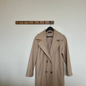 Beige Kappa - Vårkappa - GinaTricot - Vårkappa/kappa ifran GinaTricot i beige. Varm och skön. Endast använd fåtal gånger, fint skick. Säljer då den inte används. Storlek: 34 och passar 34-38. Oversized passform. Köparen star för frakt. 