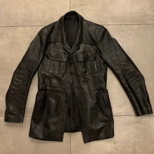 Second-hand skinnjacka - En älskad skinnjacka i svart som nu letar ny ägare!  Köpt för ca 1 år sedan second-hand för 450kr, en lite längre modell med fickor på bröstet🤩 Finns tecken på användning, ex ett litet hål i en av fickorna och en saknad knapp längst upp vid kragen. 