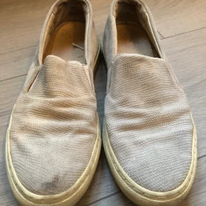 Skor Filippa K strl 38 - Gråa slip-ons från Filippa K, strl 38. Ormskinnsmönster, använda och lite fläckiga.