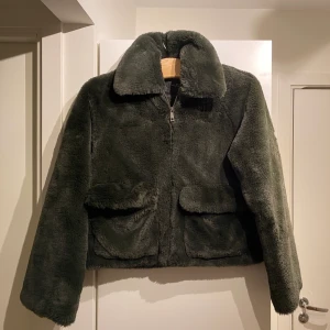Pälsjacka  - Fejkpälsjacka i mörkgrön nyans. Storlek 38 från märket Femme. Använd en gång. Kan mötas upp i Stockholm.