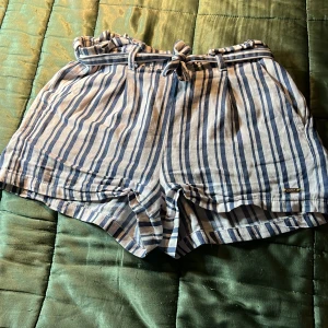 Randiga shorts - Ett par vita shorts med blåa linjer i olika storlekar med snöre. Storlek 146 men funkar på mig som är 165. Säljer för att de blir för tajta. Men det bror på om man har stora lår. 