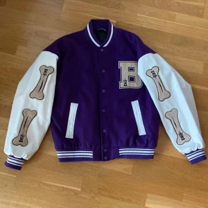 Emmiol Lila Varsity Jacka  - Emmiol Lila varsity jacka  Storlek M sitter som L/XL  Pris 299kr  Modellen är 168 och väger 58kg, har vanligtvis på sig 36 i byxor och S/XS i tröjor