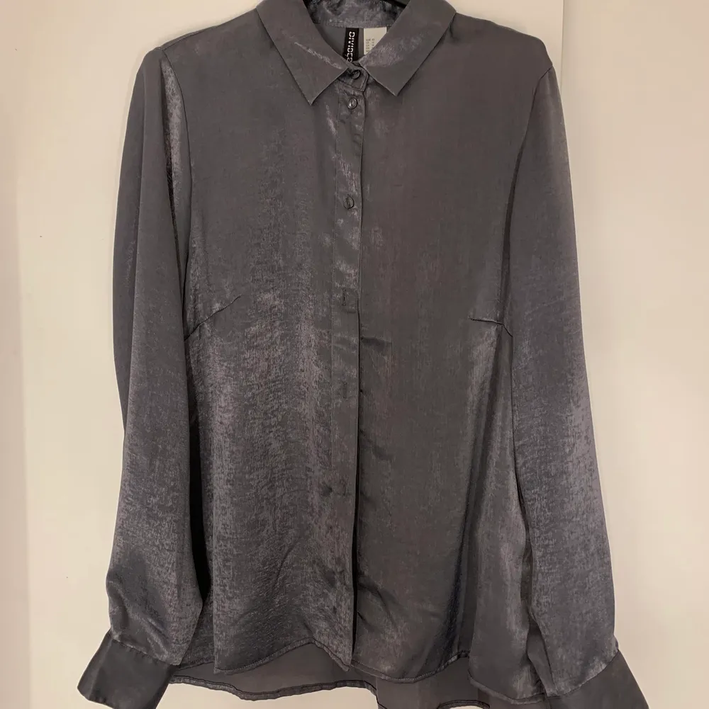 Mjuk sidenliknande skjorta ifrån H&M i grå något silverskimrande i färg. Väldigt fin kvalite men för liten på mig numera. Storlek 36. Skjortor.