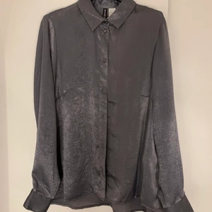 Sidenlik grå skjorta - Mjuk sidenliknande skjorta ifrån H&M i grå något silverskimrande i färg. Väldigt fin kvalite men för liten på mig numera. Storlek 36