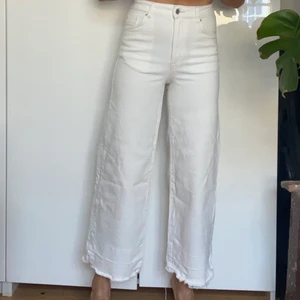 Vita croppade jeans strl 34 - Vita jeans med en avklippt kant från HM. Stretchigt material (sitter inte alls åt på mig) och inte särskilt genomskinliga (jag har svarta underkläder men syns ändå inte) 
