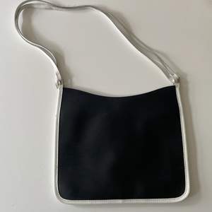 Platt svart handväska med vita och silvriga detaljer. Köpt secondhand men aldrig använt, superfint skick! 🃏