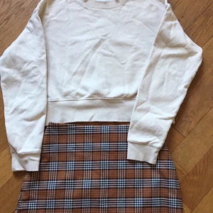 Rutig minikjol och sweatshirt - Två Monkiplagg i nyskick!Ljusbeige sweatshirt, Monki, stl xxs Brunrutig kjol, Monki, stl 36 Pris för båda plaggen: 80:-