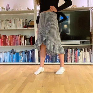 Rutig omlottkjol - Omlottkjol med volang i svartvitt rutigt tyg. Nyskick!