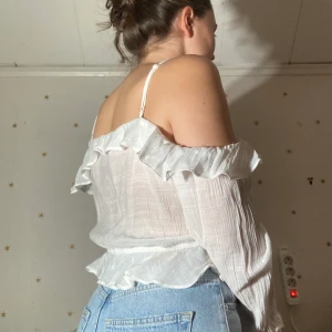 Vit blus med volanger - Från HM, justerbara band, storlek 44.  Använd en gång på skolavslutning. Jättefin men för stor för mig! Köpt för några år sedan.