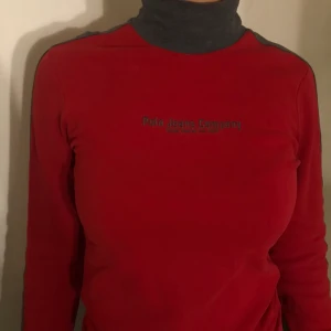 Ralph Lauren polotröja - Röd polotröja med grå polo och grå parallella ränder längs ärmen. Storlek S-M i stretchigt material.   Hämtas upp på gröna linjen mellan Skarpnäck-slussen.