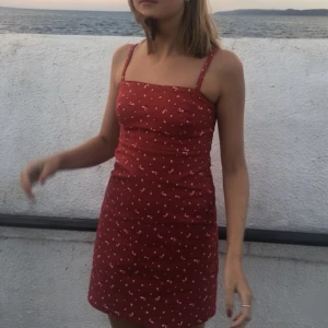 Kort klänning - röd klänning med blommigt mönster från hollister. Dragkedja vid sidan och är lite stabilare i tyget. Bra skick!