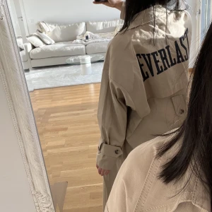Zara x Everlast trenchcoat XS-S - Oversize trenchcoat från Zaras kollektion med everlast limited edition. Endast använd ett par gånger kort stund, precis som ny! Köparen står för frakt som tillkommer på 99kr spårbart med postnord. Köptes för 1200, går ej ner i pris! 