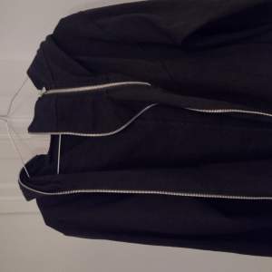 En svart hoodie med olika zippers och former som ser techwesr inspirerad ut när den är på.