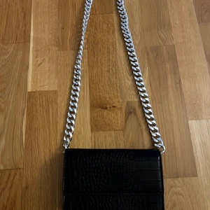 Svart Axelväska  - Svart axelväska från Gina Tricot. Köpt för 399kr. Väskan har ett dragkedje fack och två fack på var sin sida av kedjefacket. Väskan är i superfint skick. En superbra väska att bara ha nycklar och mobilen i. 