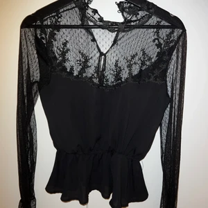 Topp - Säljer denna svarta topp som är ifrån Gina Tricot, super fin och är använd i fint skick. Storlek XS. Spets på ärmarna och bröstet och även bak i ryggen. Den har en liten spets polo krage och tröjan knäpps med knappar bak i ryggen. Den har även en liten volang där vid midjan. Säljes för 100kr plus frakt 30kr.