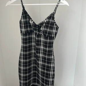 Kort svartrutig klänning - Säljer pga att den blivit för liten. Har även justerbara axelband. Den är kort men väldigt fin. Skulle även passa till någon med strl xxs