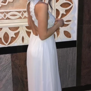 Ljusgrå långklänning i chiffongtyg - Ljusgrå långklänning i chiffongtyg, med öppen rygg i spets och virkat tyg framtill.  Storlek: 36, men passar även större storlek då den är stretch baktill.   Endast använd 1 kväll så är i nyskick.  Köpt från Nelly, nypris: ca 800 kr. Säljes för 300 kr. 