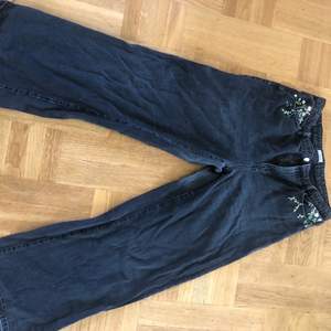 Svarta högmidjade jeans från Lindex med blommor i olika färger broderade på fickorna. Långa i benen. Storlek 44 men är lite baggy i modellen.