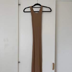 Lång brun klänning med öppen rygg, från NA-KD. Klänningen har två band som korsas och bildar en öppen rygg.