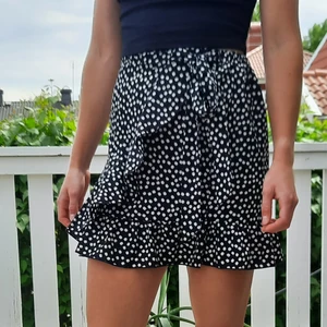 Blommig kjol strl S - En vacker svart kjol med ett mönster av vita blommor. Plagget har varit ett utav mina favorit sommarplagg. Kjolen är i mycket bra skick. Jag står inte för frakt. 