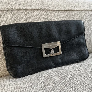 Marc Jacobs kuvertväska  - En snygg svart kuvertväska från Marc by Marc Jacobs i finaste läder. Knappt använd. Jättefint skick.   Storlek: 35cm x 19 cm.  Nypris ca 3000kr.   Kan mötas i centrala Stockholm, vid MOS eller i Uppsala. Kan även postas.