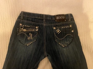 Jeans - Jättesnygga lågmidjade jeans med tuffa detaljer. Köpta här på Plick men passade tyvärr inte så jag säljer vidare. Ca 40cm i midjan och 76cm i innerbenslängden. 