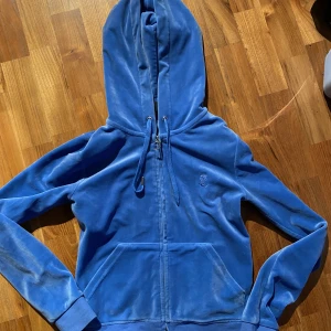 Juicy couture kofta - Juicy couture kofta i färgen Regatta. Blå. Storlek xs, passar s också. Använd fåtal gånger. Jättebra skick men ena metall detaljen på ena snöret har gått av men syns knappt. Köpare står för frakt❤️ kan även byta till en kofta i färgen Dark moss