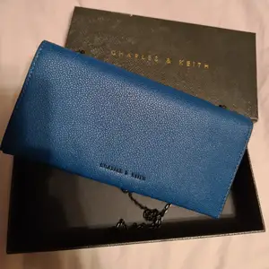Äkta Charles and keith väska/plånbok i ny skick (använt endast 1 gång & väskan kommer med originalkartong). Djupblå färg med läder. Sms mig gärna om mer information och bilder. Priset på webben är ca 600 kr.