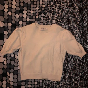 Stickad vit blus - Stickad vit blus i mjukt material. Nopprig på ena sidan nedtill. Krämvit. Kollektion: NAKD Misslisibell