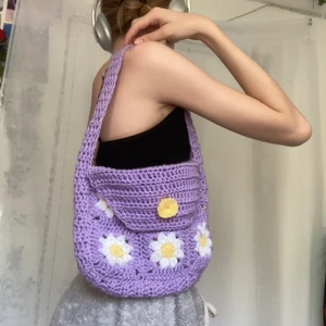 Virkad väska - Jag har virkat denna granny square väska med blommor, den är jätte fin och snygg. Den har en virkad knapp för att kunna stänga väskan. Mått:  bredd: 25cm, höjd: 20cm, djup: 5cm, Väsk bandet: 50cm