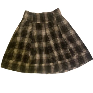 Schackrutig kjol - Längd: Ungefär till knäna (jag är 164 cm för referens) Den har fickor på sidorna vilket alltid e bra. Köpt på secondhand har dock bara använt den en gång.  det är ingen fläck vid hörnet utan det är ljuset som gör det gult