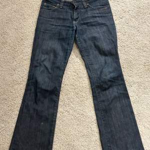 Säljer mina lågmidjade straight/lite utsvängda lee jeans i mörk tvätt, då de blivit för små. Sjukt snygga och speciella! Lite slitna vid rumpan som, men endast det som syns på bilden. Midjemått 38 cm, innerben 78 cm.