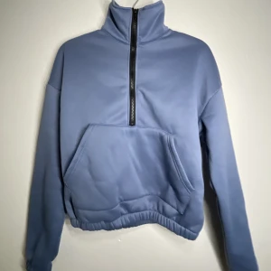 Blå tröja  - Ljusblå tröja med dragkedja och hög krage 