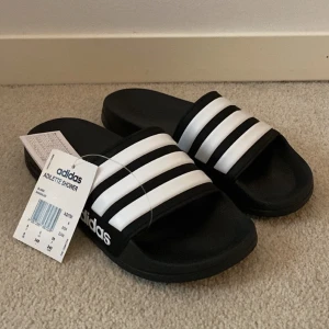 Adidas tofflor - Säljer ett par helt oanvända Adidas tofflor! Har redan ett par exakt likadana, så har ingen användning för dessa☺️ Orginal pris 299kr!