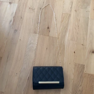 Väska - Säljer denna as snygga svarta väska med guld kedja💞 Säljer för att den ej kommer till användning och den är bara testad  1 gång. Priset kan diskuteras och jag akn mötas upp i gbg  Köparen står för frakt. Priset går att diskuteras 