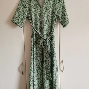 Grön klänning med blommor - Vacker och somrig klänning i retro-stil. Den är grön (lite grönare än bilderna) med vita blommor. Den saknar tyvärr lapp med storlek men passar en storlek S. 
